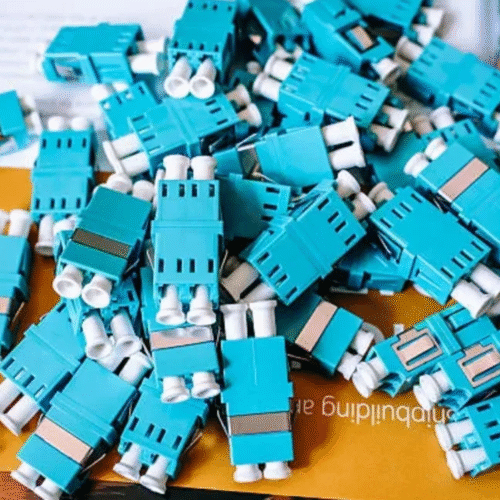 A pile of aqua duplex LC fiber optic adapters.