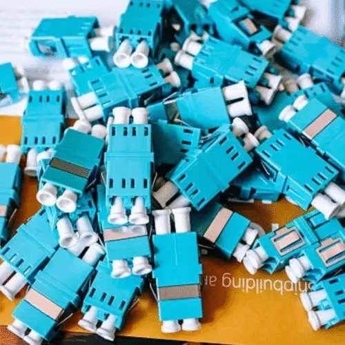A pile of aqua duplex LC fiber optic adapters.