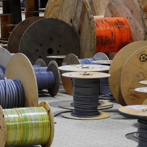 Wooden reels of fiber optic and telecom cable stored in a warehouse.