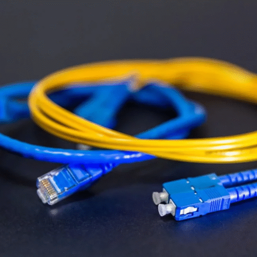 Yellow single-mode fiber patch cord with blue SC connectors, beside a blue Ethernet cable.